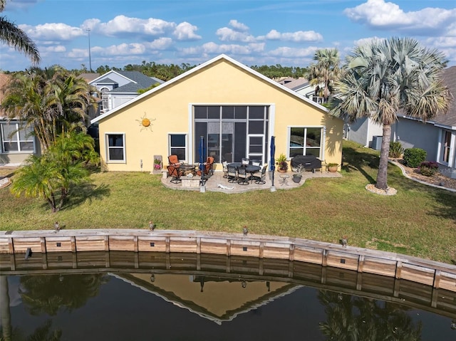 back of property featuring a water view, a yard, a patio, and a fire pit