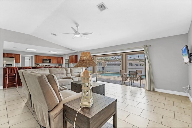 living room with visible vents, a ceiling fan, light tile patterned flooring, baseboards, and vaulted ceiling