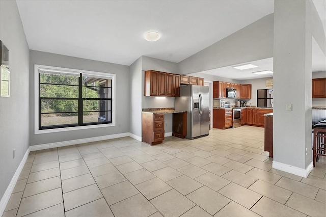 kitchen featuring lofted ceiling, baseboards, and appliances with stainless steel finishes