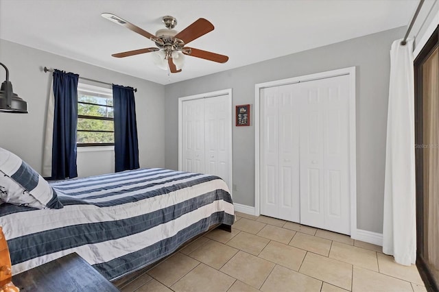 bedroom with light tile patterned floors, baseboards, multiple closets, and ceiling fan