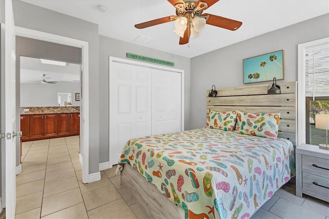 bedroom with light tile patterned floors, a ceiling fan, a closet, and baseboards