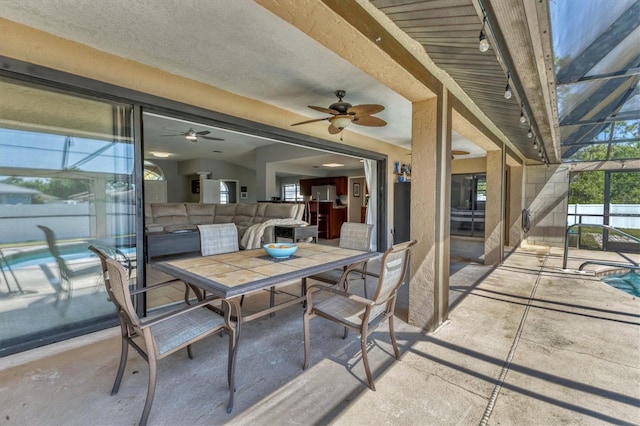 view of patio with fence, a lanai, outdoor dining area, a fenced in pool, and ceiling fan