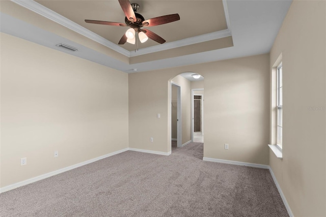 carpeted spare room with a tray ceiling, ornamental molding, and a healthy amount of sunlight