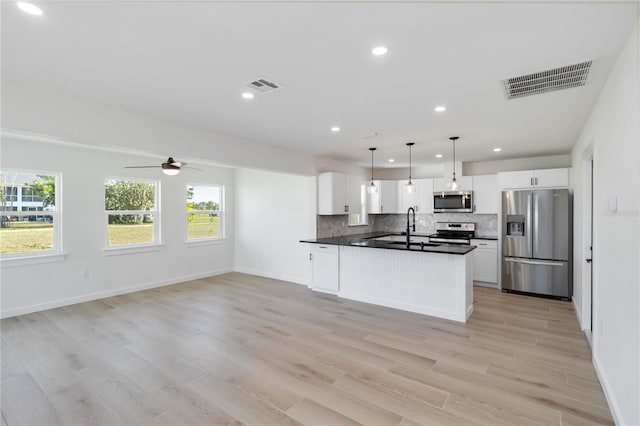 kitchen with pendant lighting, white cabinetry, backsplash, light hardwood / wood-style floors, and stainless steel appliances