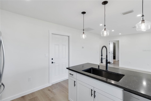 kitchen with white cabinetry, sink, decorative light fixtures, and light hardwood / wood-style floors