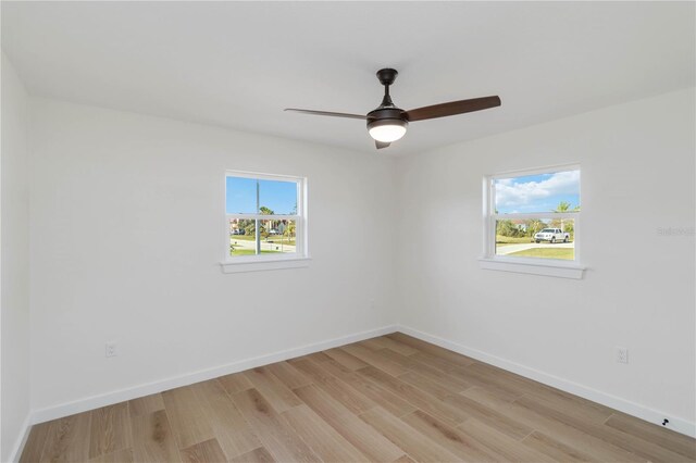 empty room with ceiling fan and light hardwood / wood-style flooring