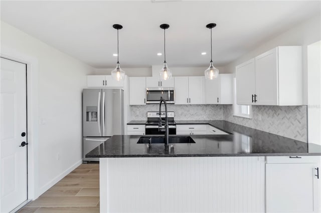 kitchen featuring sink, white cabinetry, appliances with stainless steel finishes, dark stone counters, and backsplash