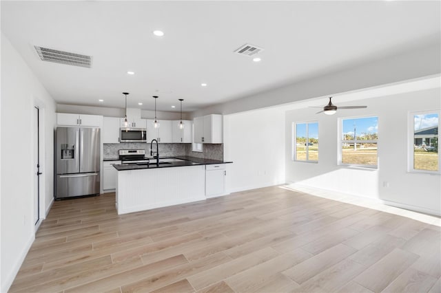 kitchen with sink, white cabinetry, hanging light fixtures, backsplash, and stainless steel appliances