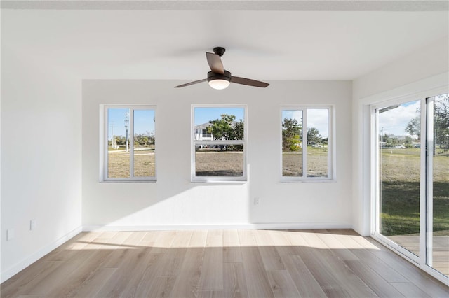 empty room featuring a healthy amount of sunlight, ceiling fan, and light hardwood / wood-style flooring