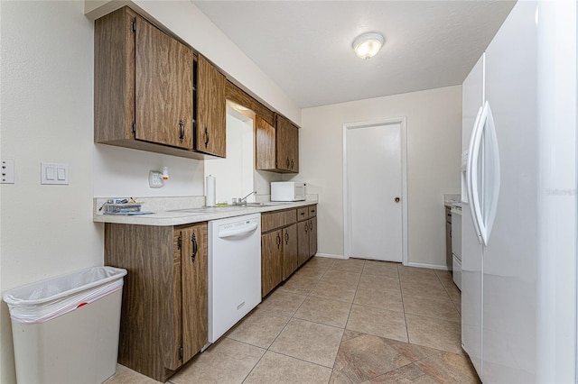 kitchen featuring sink, light tile patterned floors, and white appliances