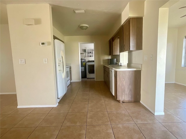 kitchen with light tile patterned flooring, white appliances, washer / dryer, and sink