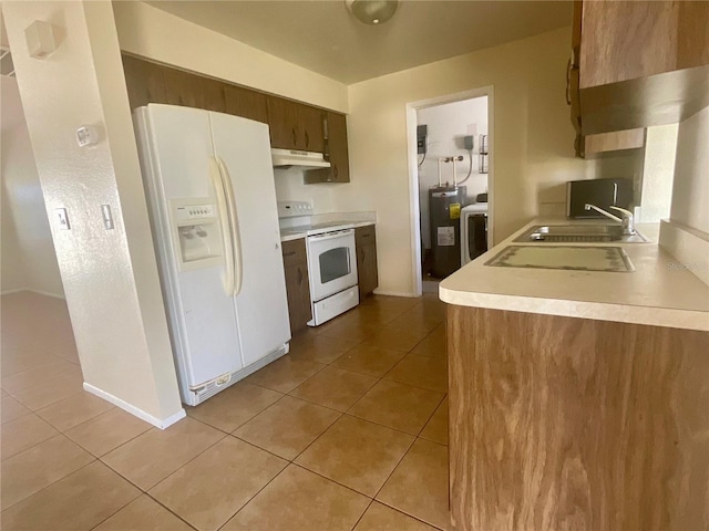 kitchen with light tile patterned flooring, white appliances, washer / clothes dryer, and sink