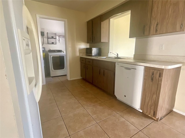 kitchen with washer / clothes dryer, dishwasher, sink, and light tile patterned floors