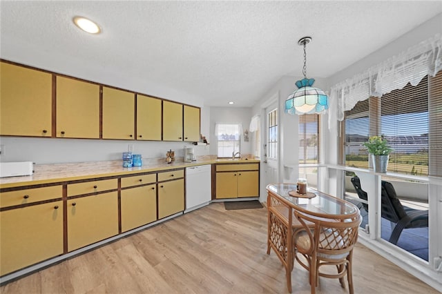 kitchen featuring white dishwasher, decorative light fixtures, a textured ceiling, and light wood-type flooring