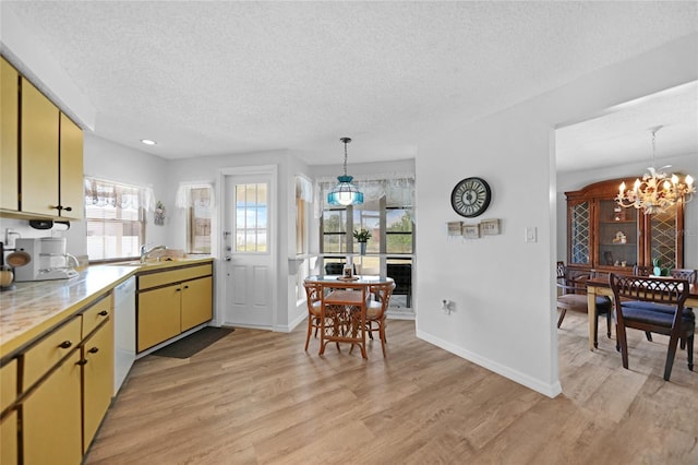 kitchen with decorative light fixtures, a chandelier, a textured ceiling, light wood-type flooring, and white dishwasher