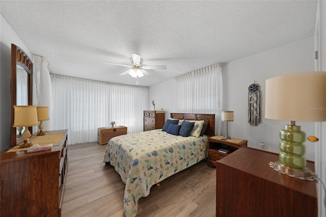 bedroom with ceiling fan, a textured ceiling, and light hardwood / wood-style floors