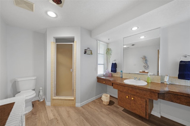 bathroom featuring hardwood / wood-style floors, vanity, an enclosed shower, toilet, and a textured ceiling