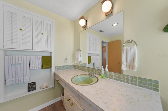 bathroom with vanity, hardwood / wood-style floors, a textured ceiling, and backsplash