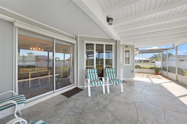 unfurnished sunroom with beamed ceiling and an inviting chandelier