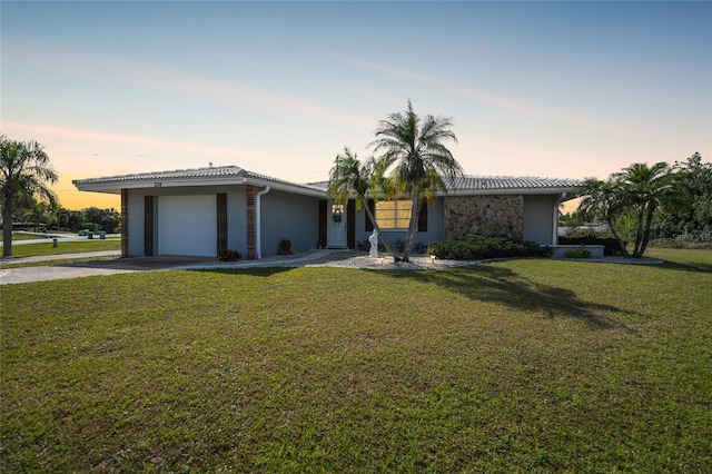 ranch-style home featuring a garage and a lawn