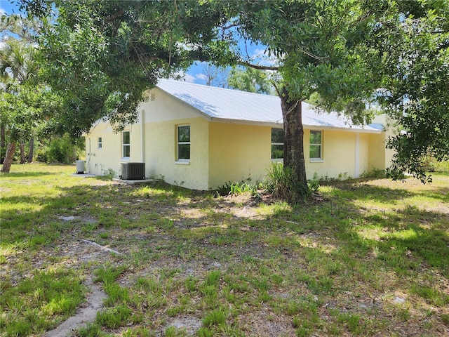 view of side of home with a lawn and central air condition unit