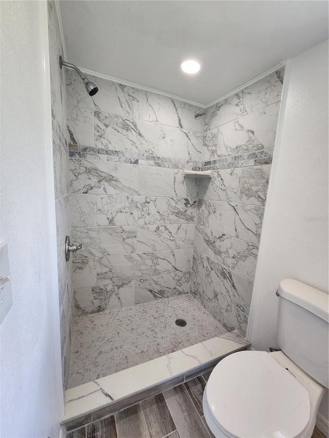 bathroom with hardwood / wood-style floors, toilet, and tiled shower