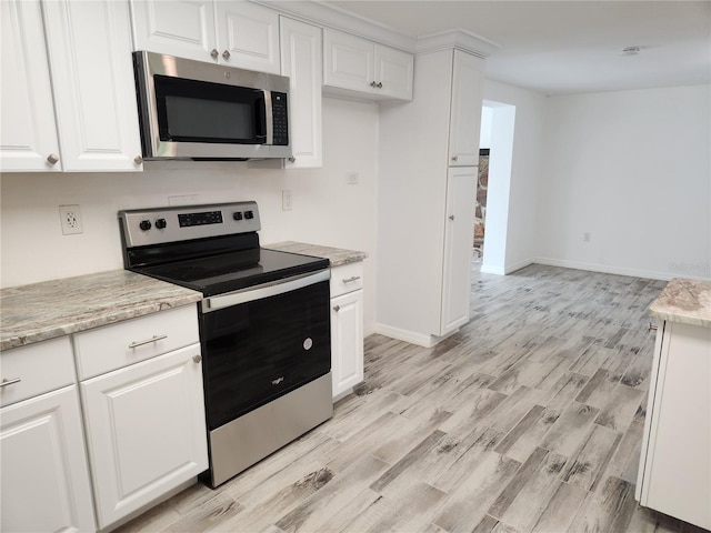 kitchen featuring white cabinetry, light stone counters, light hardwood / wood-style flooring, and appliances with stainless steel finishes