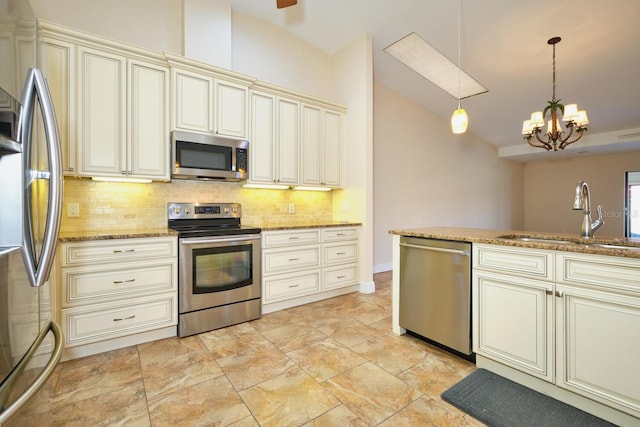 kitchen with stone countertops, sink, hanging light fixtures, stainless steel appliances, and cream cabinetry