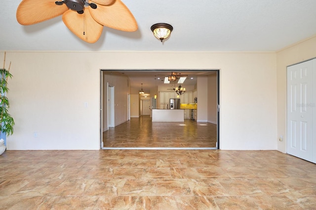 spare room featuring crown molding and ceiling fan with notable chandelier