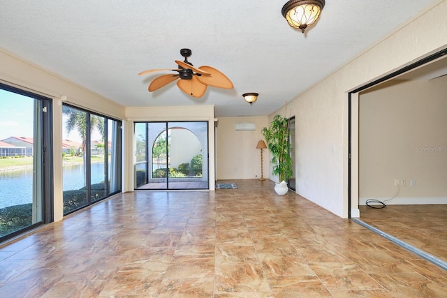 empty room with a textured ceiling, a wall unit AC, ceiling fan, and a water view