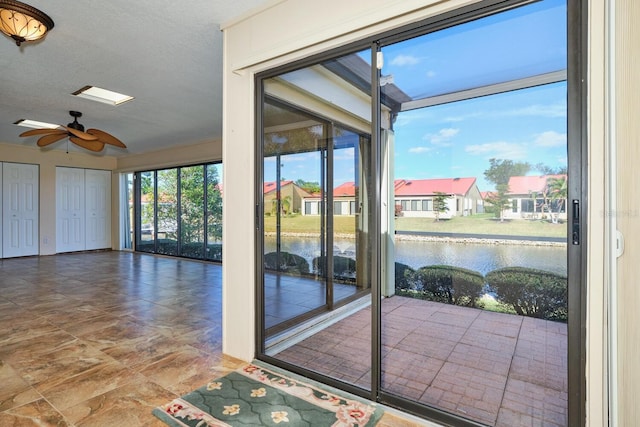 entryway with ceiling fan, a textured ceiling, and a water view