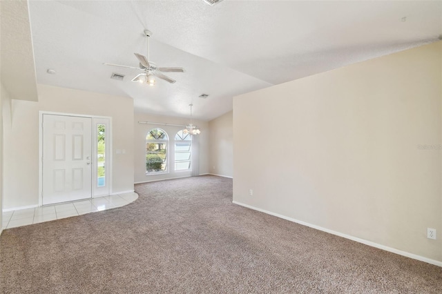 unfurnished living room with vaulted ceiling, ceiling fan with notable chandelier, light colored carpet, and a textured ceiling