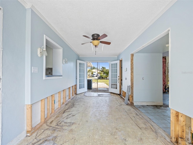 foyer with french doors, ceiling fan, ornamental molding, and a textured ceiling