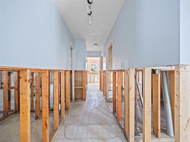 hall featuring track lighting and a textured ceiling