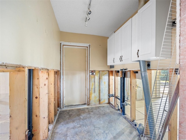 interior space featuring cabinets, track lighting, and a textured ceiling