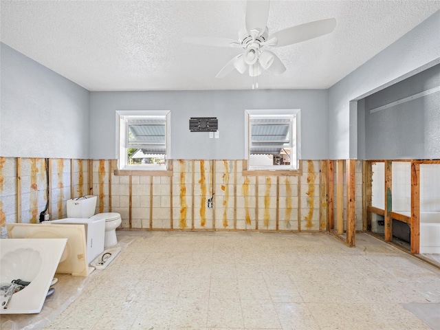 bathroom featuring tile walls, ceiling fan, toilet, and a textured ceiling