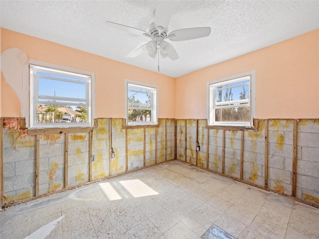 empty room with ceiling fan, tile walls, and a textured ceiling