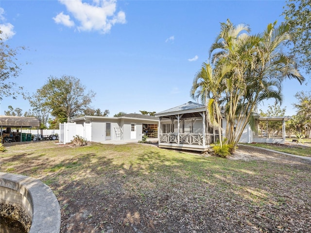 rear view of house featuring a sunroom and a lawn