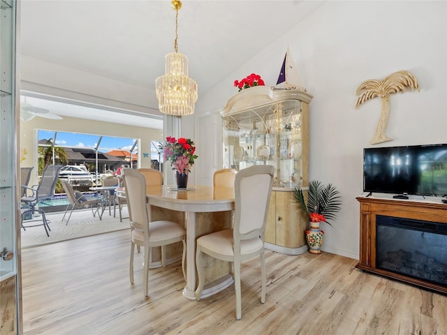 dining area featuring lofted ceiling, light hardwood / wood-style flooring, and a chandelier