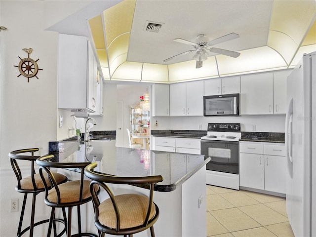 kitchen with white refrigerator, kitchen peninsula, white cabinets, and electric stove