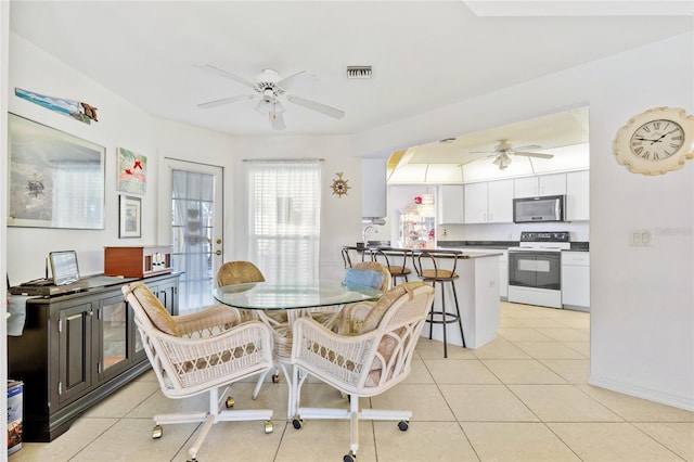 tiled dining space featuring ceiling fan and sink