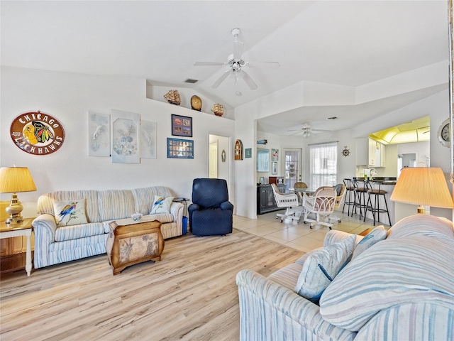 living room with ceiling fan, vaulted ceiling, and light hardwood / wood-style flooring