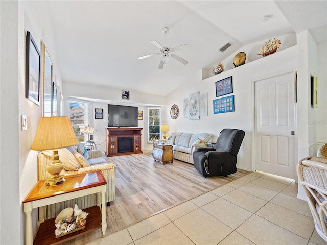 living room with lofted ceiling, light tile patterned floors, and ceiling fan