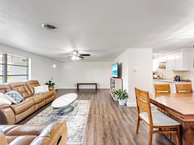 living room featuring sink, light hardwood / wood-style flooring, and ceiling fan