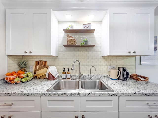 kitchen with sink, white cabinets, light stone counters, and decorative backsplash