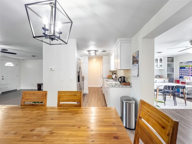 kitchen with light stone countertops, white cabinets, ceiling fan, and light hardwood / wood-style floors