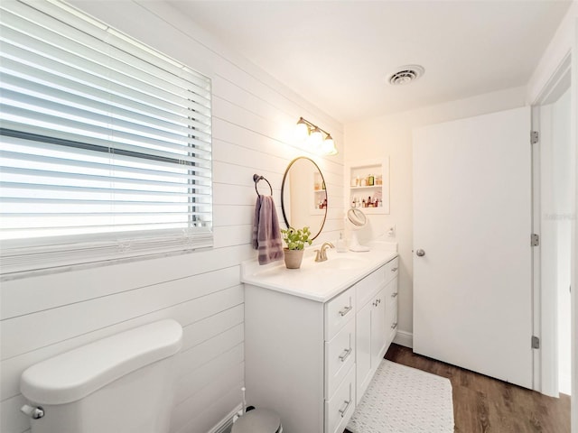 bathroom with vanity, hardwood / wood-style flooring, wooden walls, and toilet