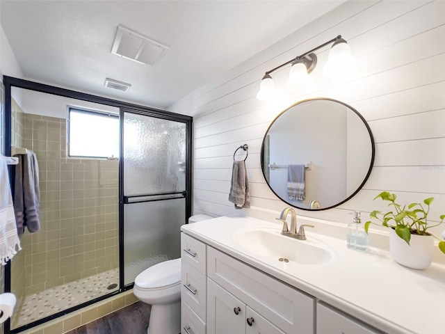 bathroom with hardwood / wood-style floors, an enclosed shower, vanity, toilet, and wood walls