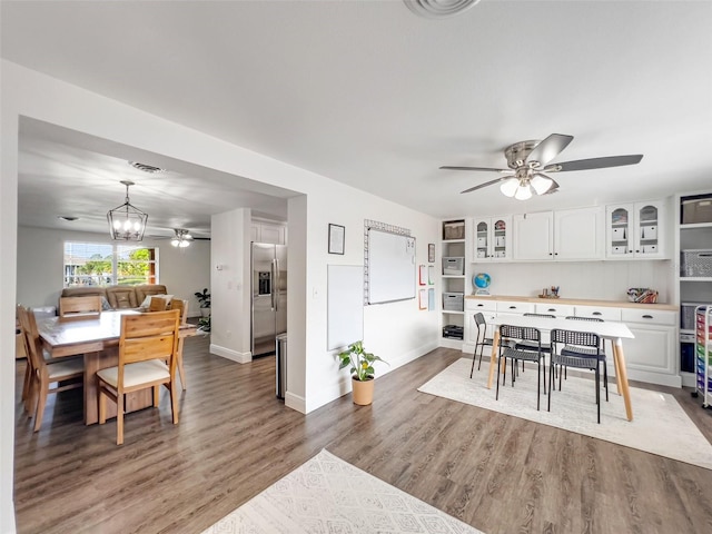 dining space with hardwood / wood-style flooring and ceiling fan with notable chandelier