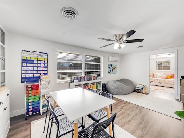 dining space featuring ceiling fan, wood-type flooring, and a wall mounted AC